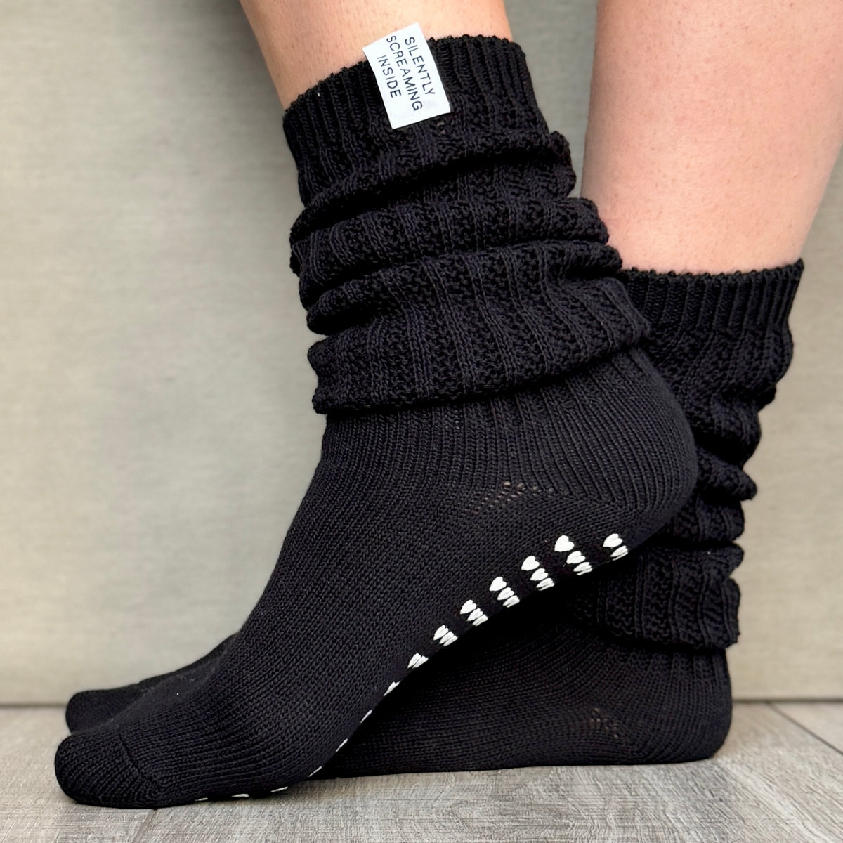 A pair of black slouch socks with grip pads on the sole, featuring a cozy, casual style.