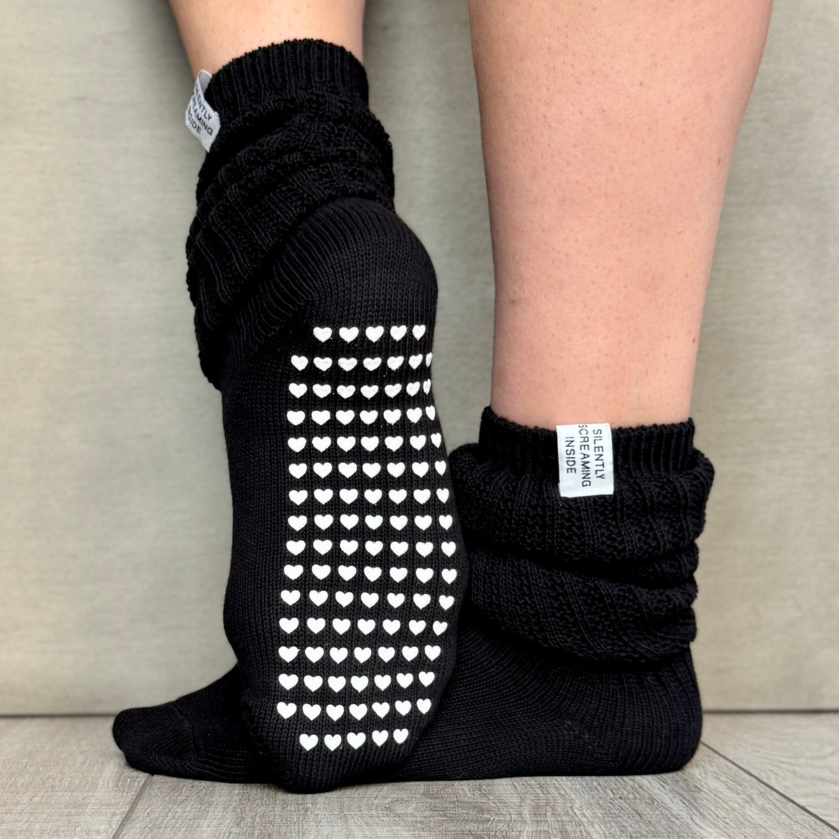 black slouch socks with a fabric tag that reads silently screaming and white heart shaped non slip grips